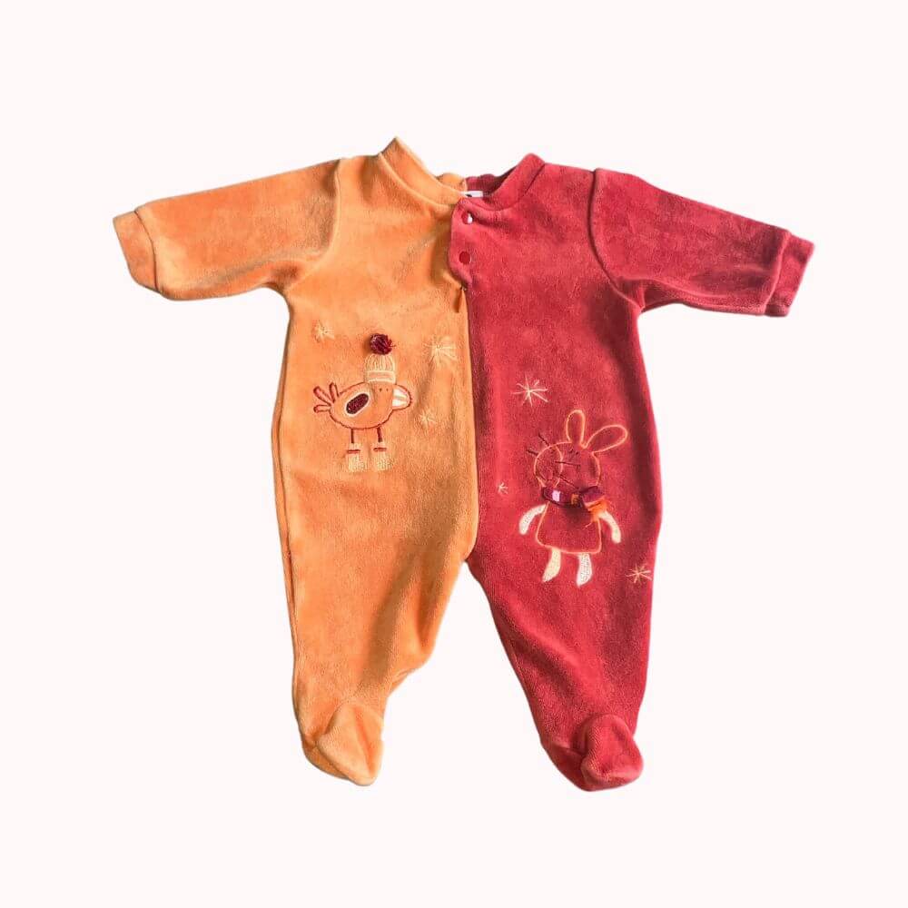 Pyjama avec pieds intégrés, côté droit de couleur entièrement saumon avec motif poule brodé, côté gauche de couleur rose foncé avec motif lapin brodé , tout ceci est symétrique. Fermeture éclair sur le devant .