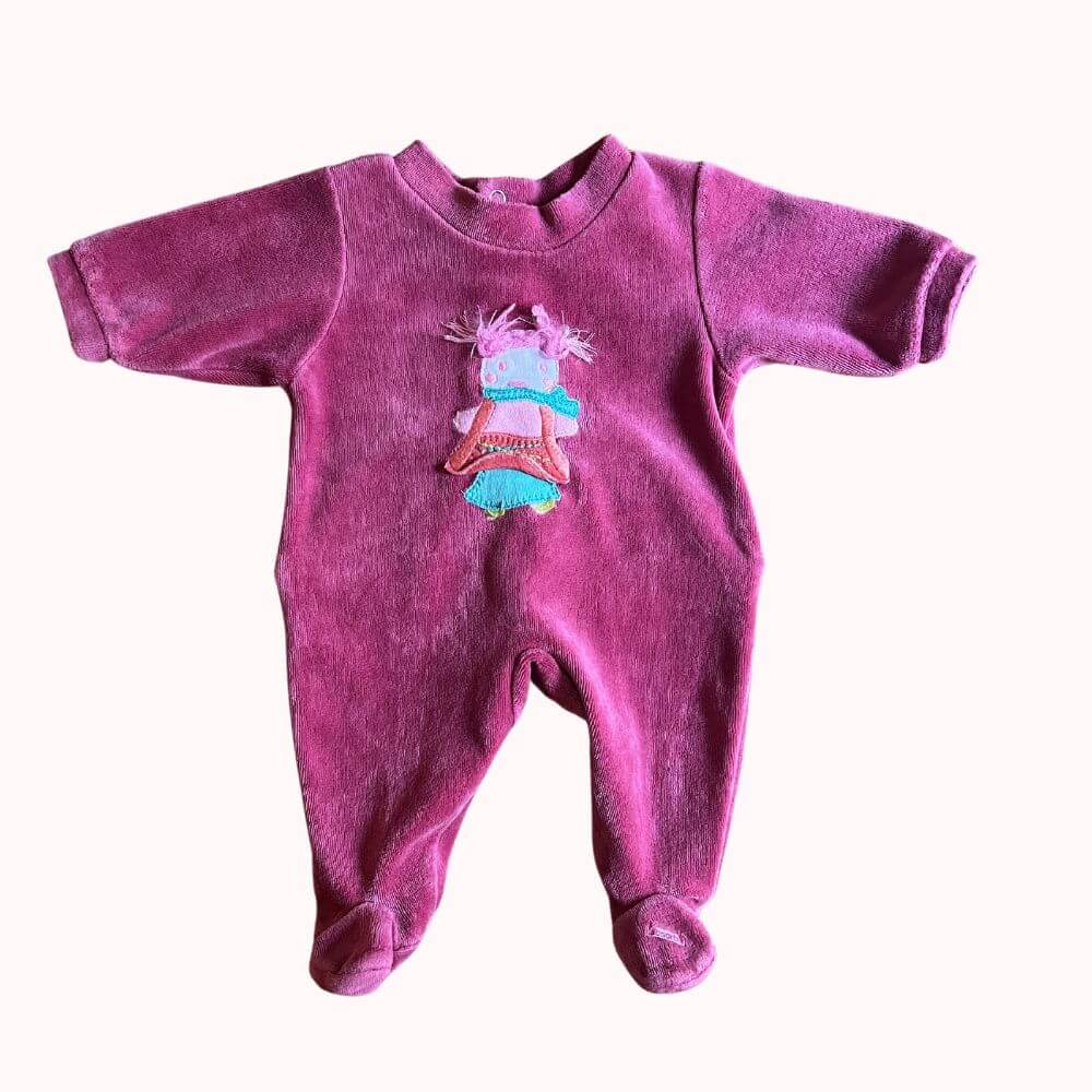 Pyjama couleur framboise avec pieds intégrés, poupée rigolote en relief de couleurs bleue, rose et grise avec des cheveux en vraie laine rose sur le devant .