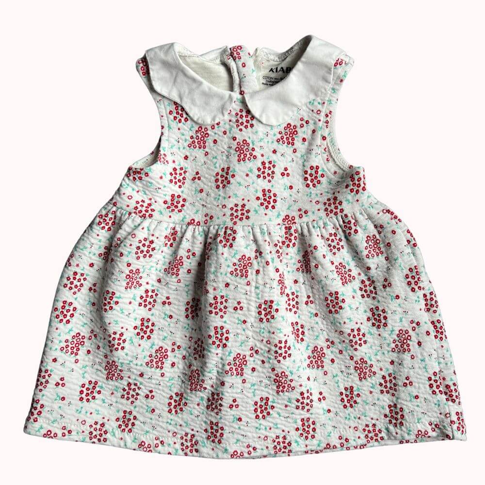 Robe blanche sans manches pour enfant, imprimé floral rouge, col claudine blanc, avec fermeture éclair invisible dans le dos, en très bon état.
