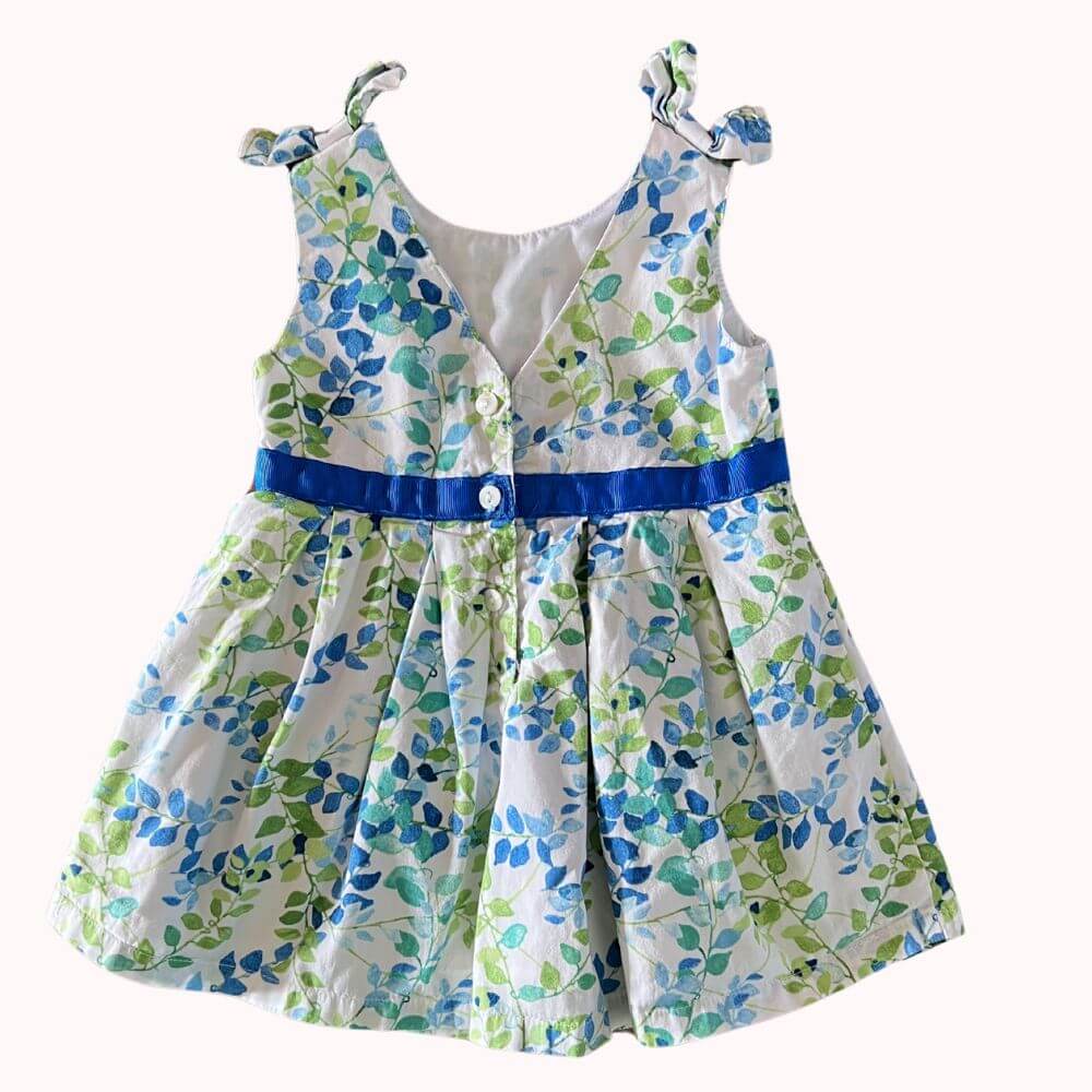 Robe blanche pour bébé fille de 9 mois, à motifs de feuilles bleues et vertes, avec ruban bleu à la taille et bretelles à nouer.