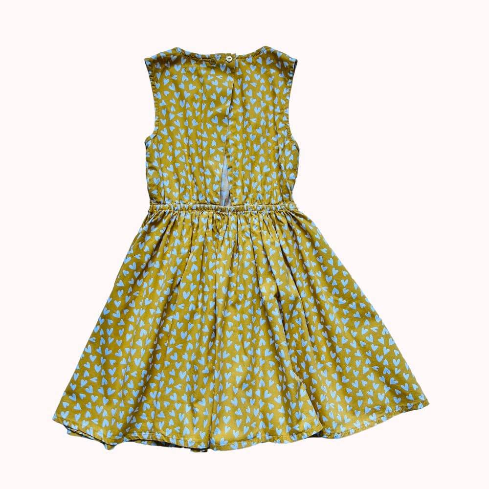 Robe de dos sans manches jaune ocre à imprimé cœurs bleus, taille élastiquée et fermeture boutonnée au dos.