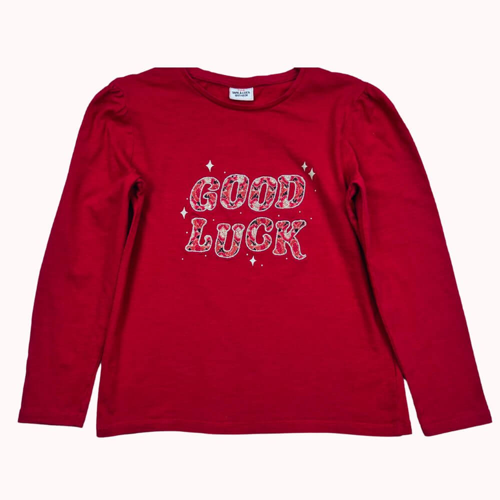 T-shirt manches longues rouge Tape à l’Œil 10 ans avec inscription "GOOD LUCK" scintillante.