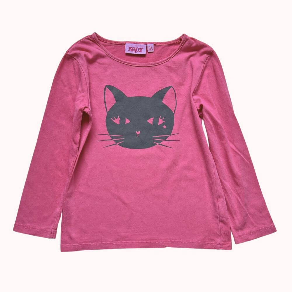T-shirt rose à manches longues pour enfant, imprimé d’un grand motif tête de chat noir avec détails étoilés dans les yeux.