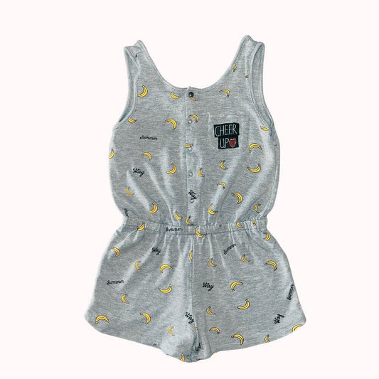 Combi-short fille grise IKKS 10 ans (XXS), imprimée de bananes jaunes et mots noirs, avec boutons pression devant, taille élastiquée et écusson "Cheer Up" sur la poitrine.