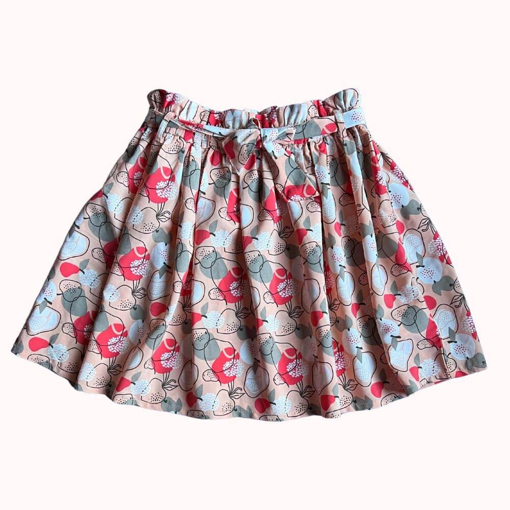 Jupe pour enfant avec imprimé floral coloré, taille élastiquée et nœud décoratif à la ceinture, en très bon état.