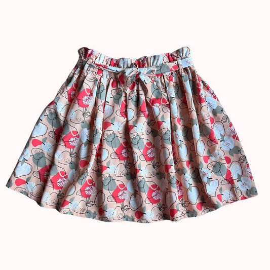 Jupe pour enfant avec imprimé floral coloré, taille élastiquée et nœud décoratif à la ceinture, en très bon état.