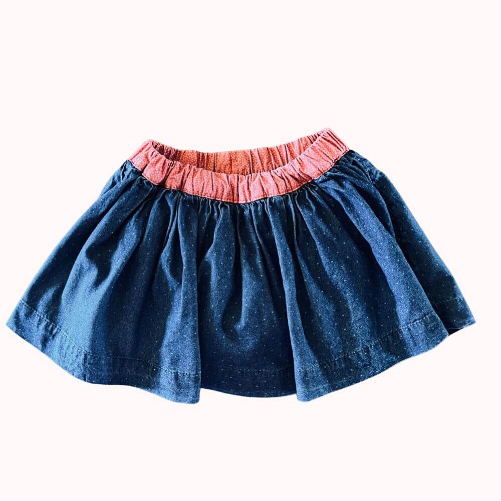 Jupe en jean bleu pour bébé avec taille élastiquée contrastante et bloomer intégré, coupe ample et fluide.