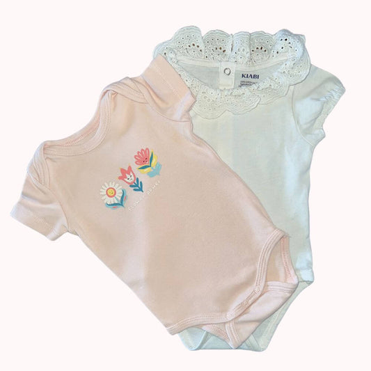 Lot de deux bodies bébé KIABI taille 3 mois : un rose à imprimé "flower power", un blanc avec col en broderie anglaise.