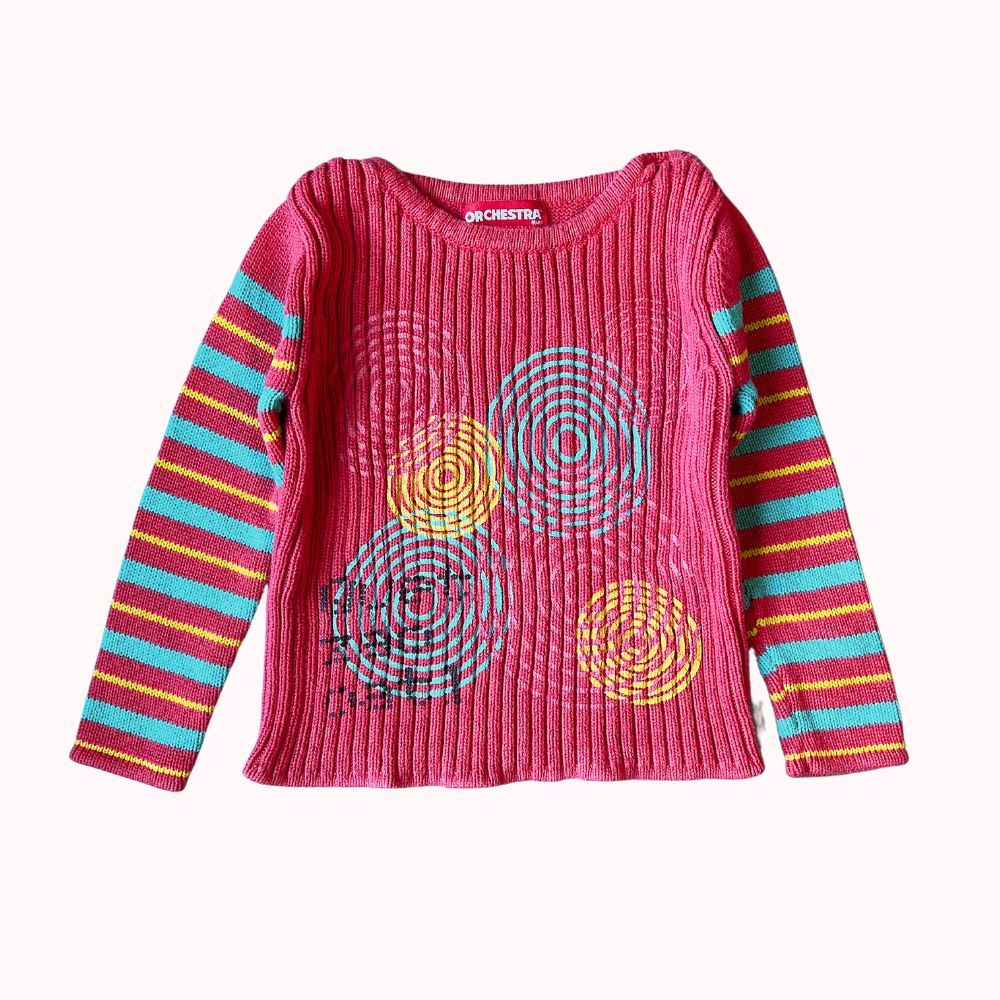  Pull rose à manches longues pour enfant, marque Orchestra, avec motifs circulaires colorés sur le devant et manches rayées multicolores.