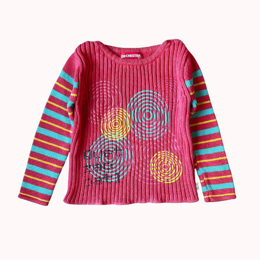  Pull rose à manches longues pour enfant, marque Orchestra, avec motifs circulaires colorés sur le devant et manches rayées multicolores.