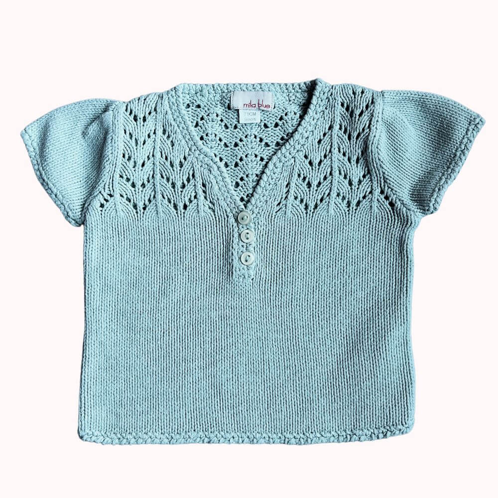 Haut en tricot vert pastel pour fille, manches courtes, avec détails ajourés et boutons décoratifs, en bon état.