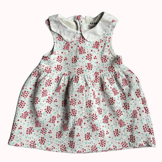Robe blanche sans manches pour enfant, imprimé floral rouge, col claudine blanc, avec fermeture éclair invisible dans le dos, en très bon état.