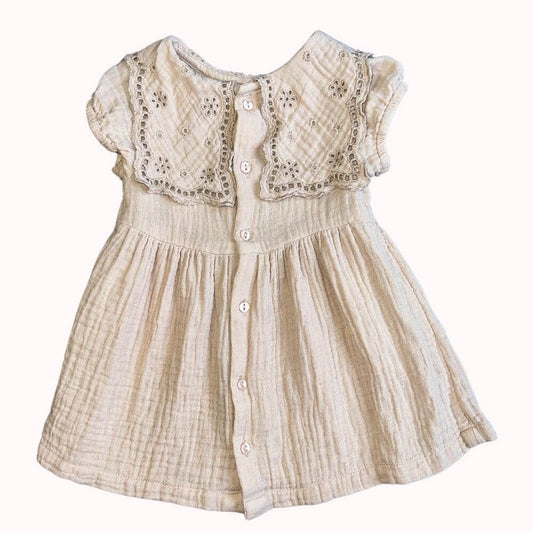 Robe beige en coton crêpe pour enfant, avec col brodé ajouré, boutons dans le dos, et coupe fluide, en très bon état.