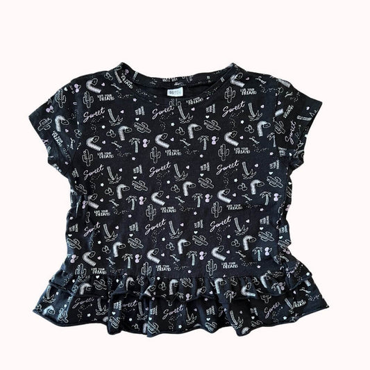  T-shirt noir fille 3-4 ans avec imprimés fantaisie blancs et pastels, manches courtes, inscription “Sweet” en rose et petit volant en bas.