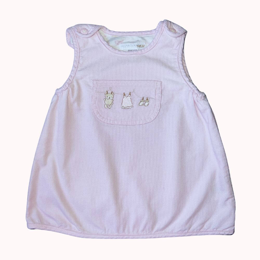Robe en velours rose H&M pour bébé 2-4 mois, avec motifs brodés sur la poche avant et fermeture à boutons-pression.