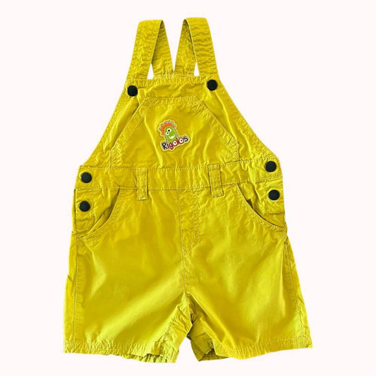  Salopette courte jaune pour bébé, marque DPAM, motif "Rigolos" brodé, taille 18 mois, avec boutons pressions aux bretelles et sur les côtés.