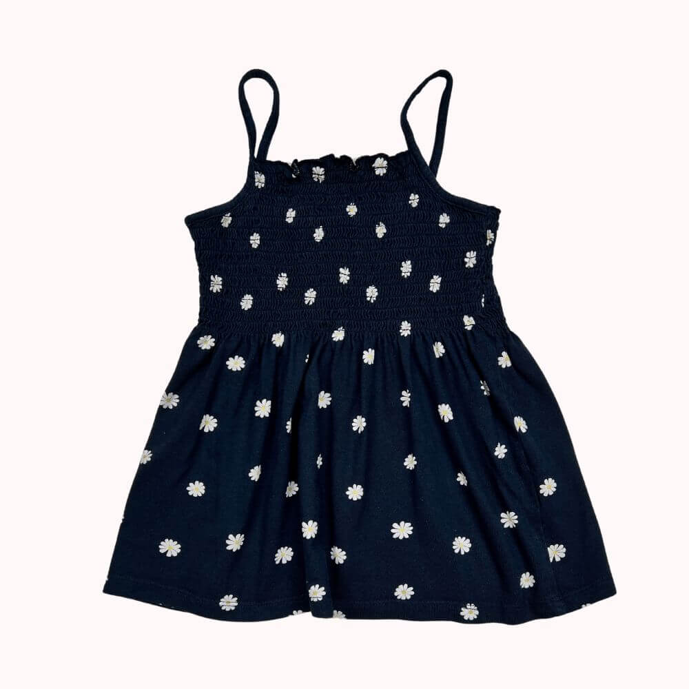 Top noir à fines bretelles avec smocks sur le buste et imprimé fleuri blanc, coupe évasée et légère.