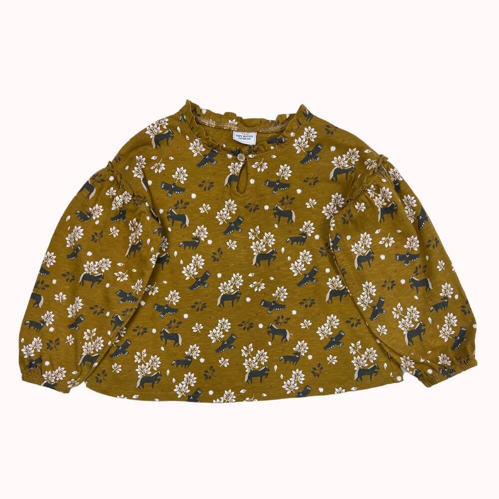 Tunique enfant ocre imprimée avec motifs animaux et fleurs, manches longues bouffantes, fermeture boutonnée à l’encolure.