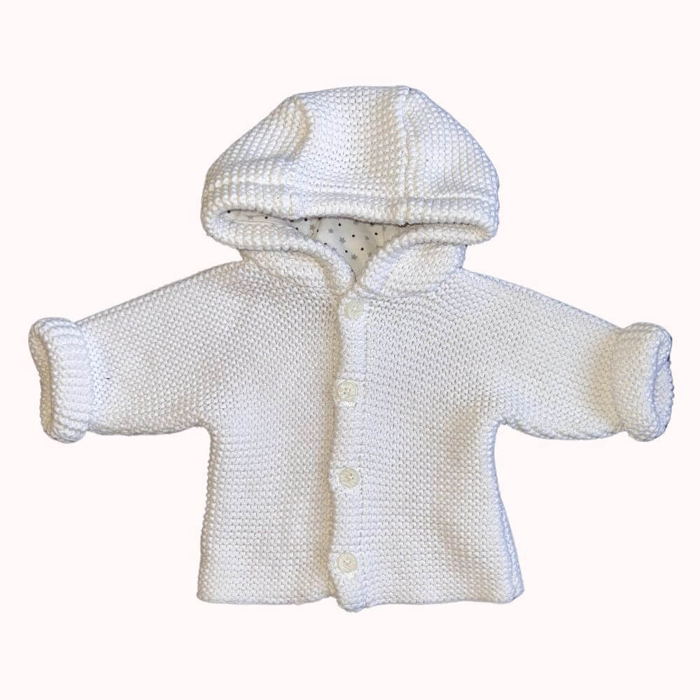 Gilet en maille blanche pour bébé, avec capuche doublée motifs étoiles, boutons sur le devant et manches retroussables, en très bon état.